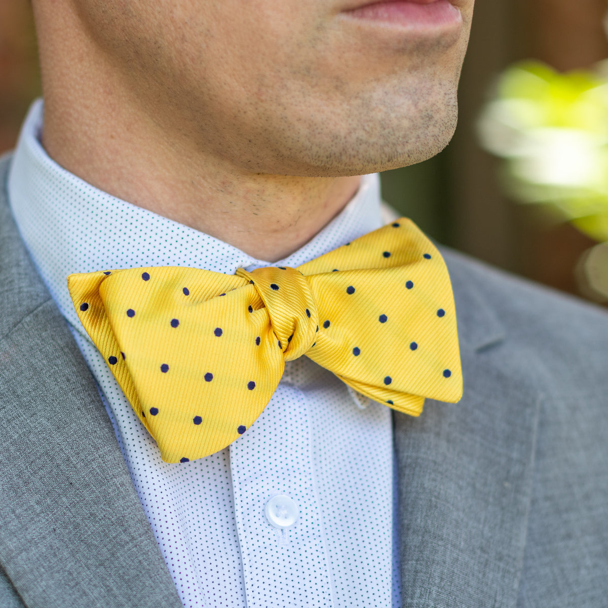 Yellow and blue polka dot bow tie with gray suit outfit