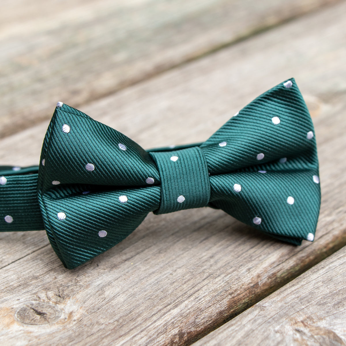 Green with white polka dot boys pre-tied bow tie shown on wood