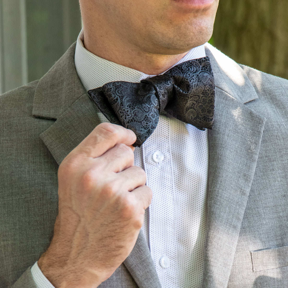 Black paisley woven silk bow tie shown with light gray suit